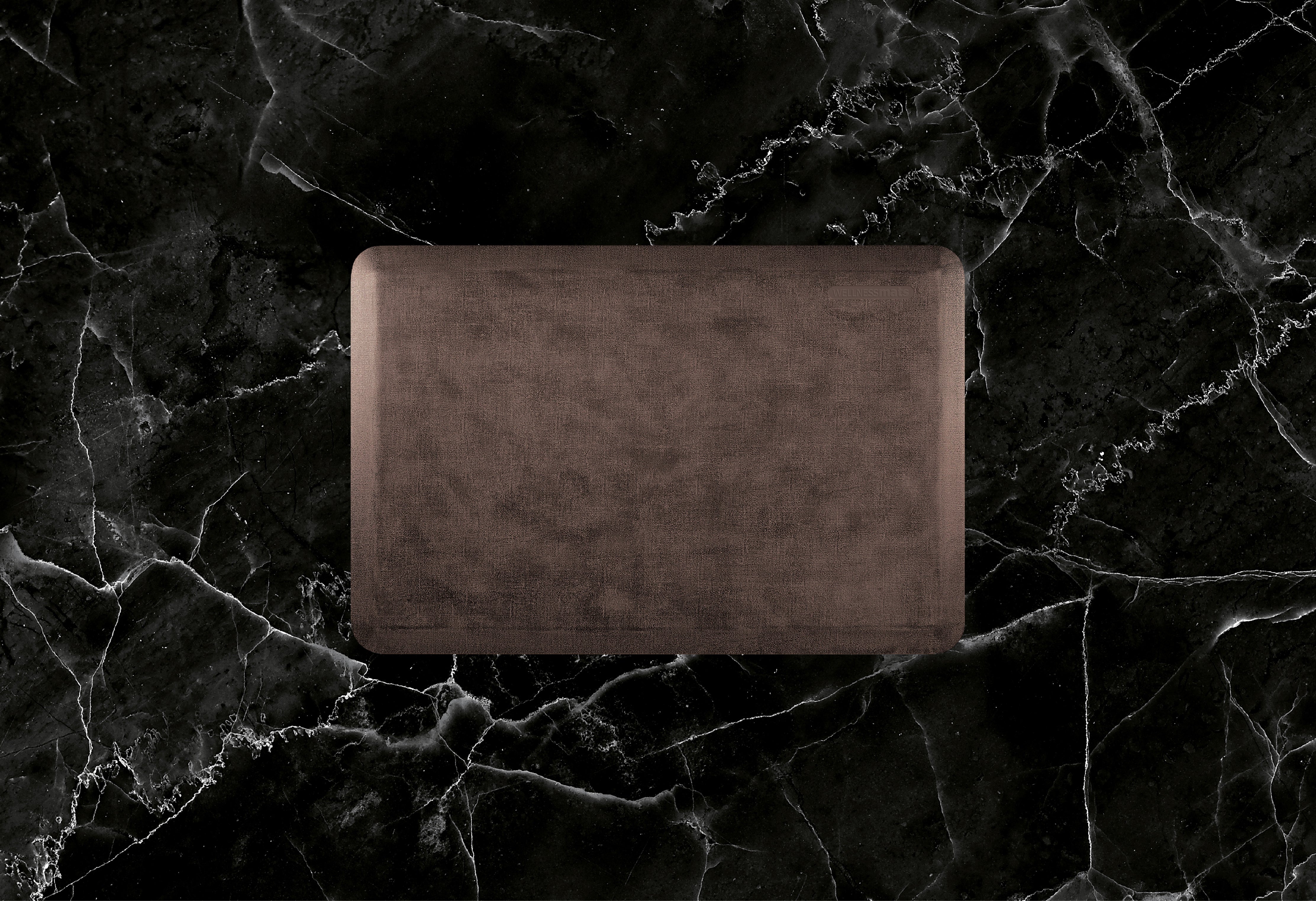 A 3'x2' Antique Dark WellnessMat on a black marble floor.