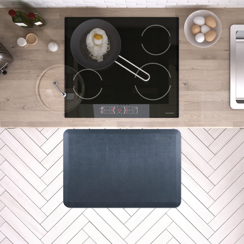 A 3'x2' Linen Lagoon WellnessMat in front of a kitchen stove.