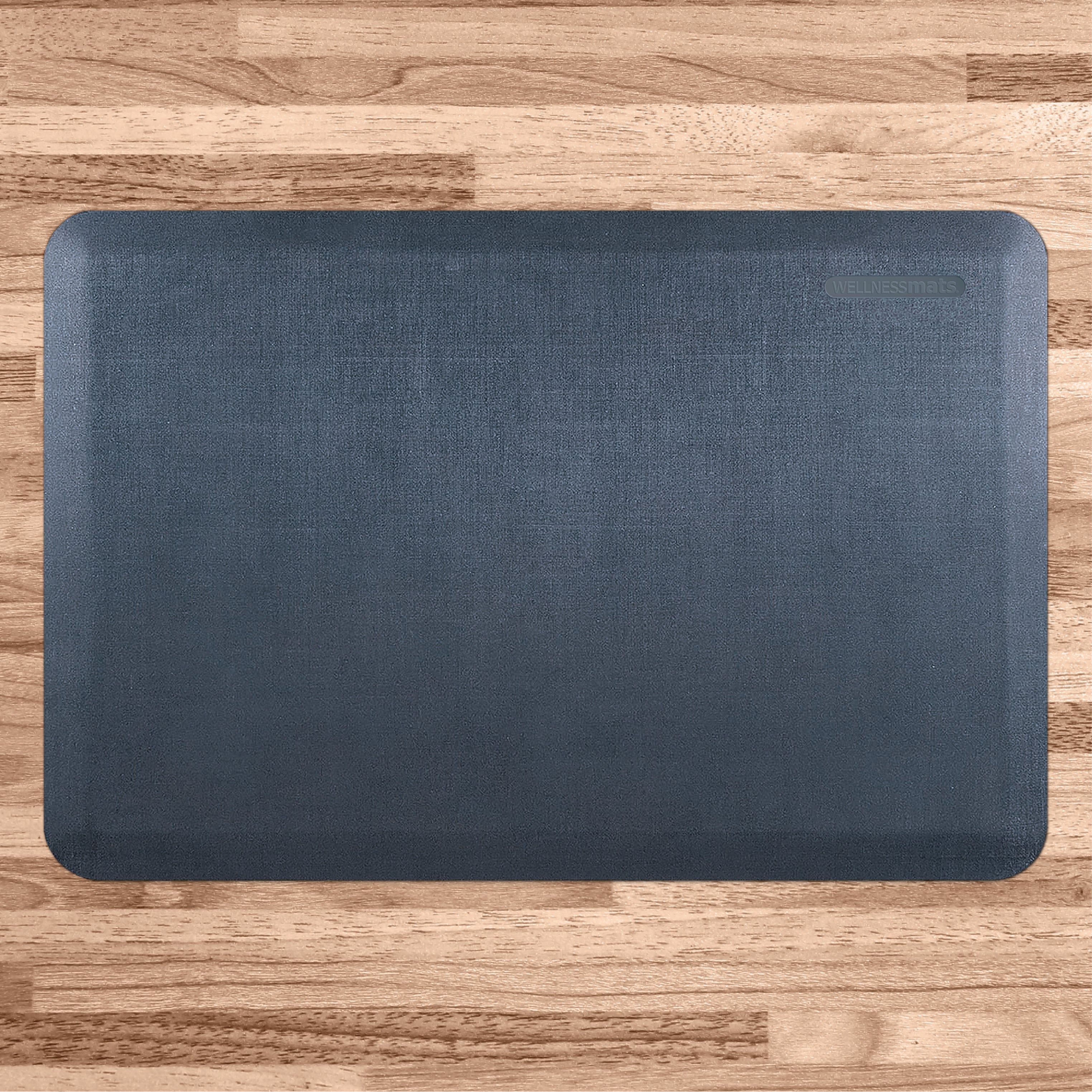 A 3'x2' Linen Lagoon WellnessMat on a  light wood floor.