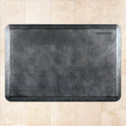 A 3'x2' Linen Onyx WellnessMat on a tile floor