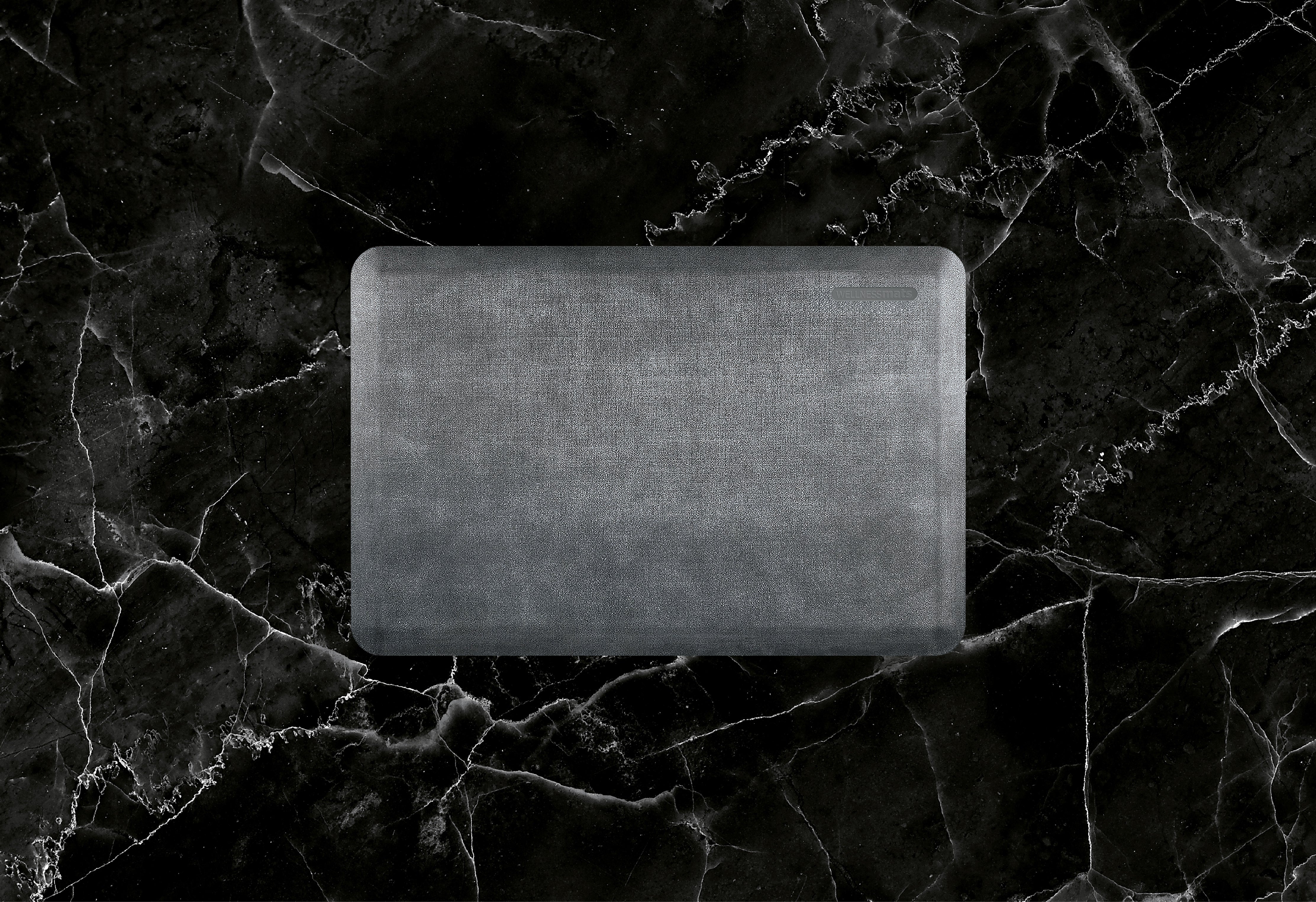 A 3'x2' Linen Slate WellnessMat on black marble. 
