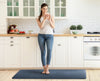 A woman standing on a 6'x2' lagoon WellnessMat in a kitchen. 