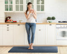 A woman standing on a 6'x2' lagoon WellnessMat in a kitchen. 