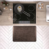 A 3'x2' Antique Dark WellnessMat in front of a kitchen stove.
