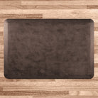 A 3'x2' Antique Dark WellnessMat on a light wood floor.