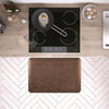 A 3'x2' Antique Light WellnessMat in front of a kitchen stove.