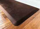 An up-close shot of a 6'x2' Antique Dark WellnessMat on a light wood floor.